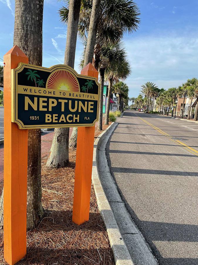 Welcome to Neptune Beach sign on a palm-lined street