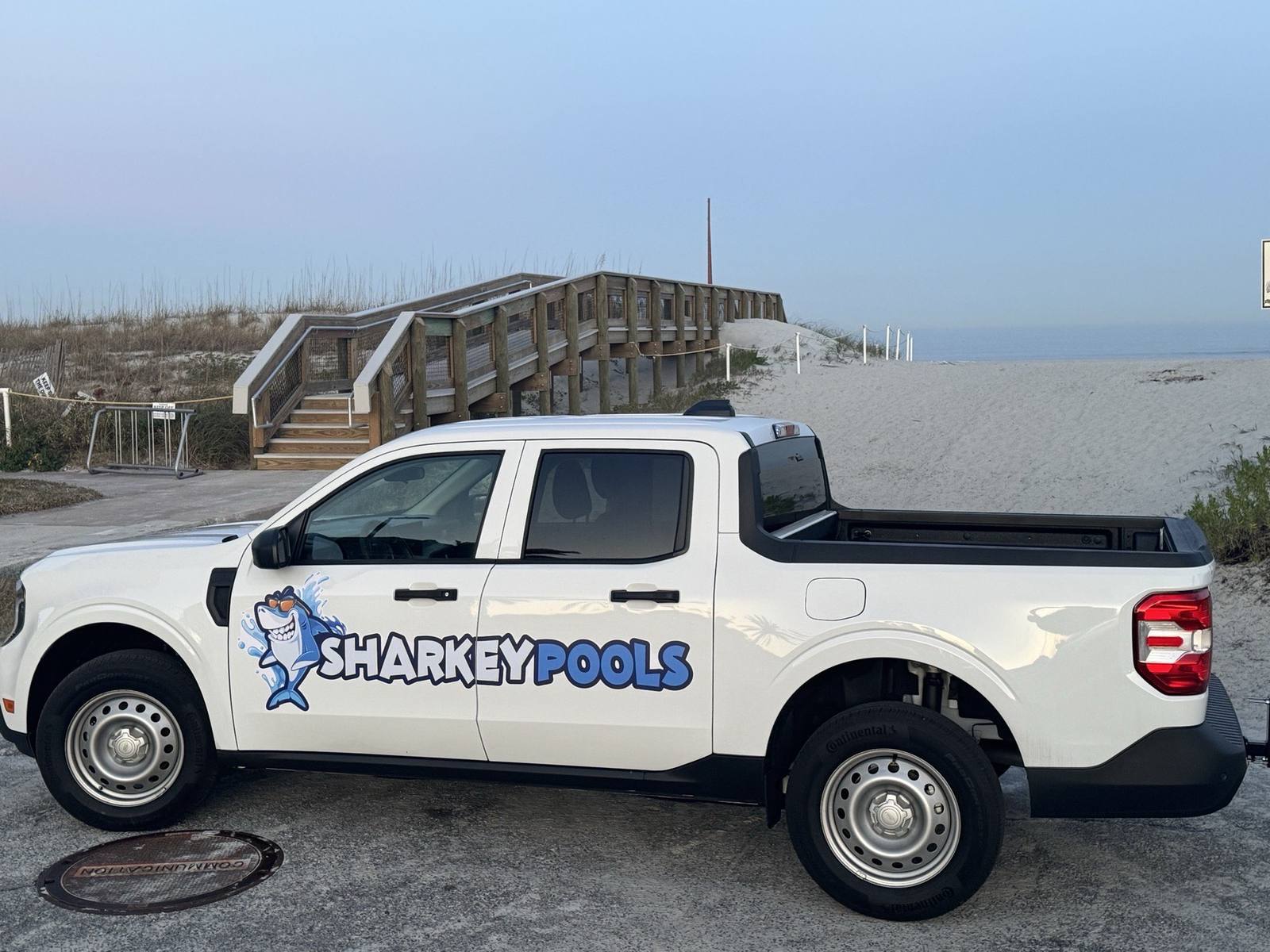 Sharkey Pools service truck parked by a Jacksonville Beach dune walkover at sunrise
