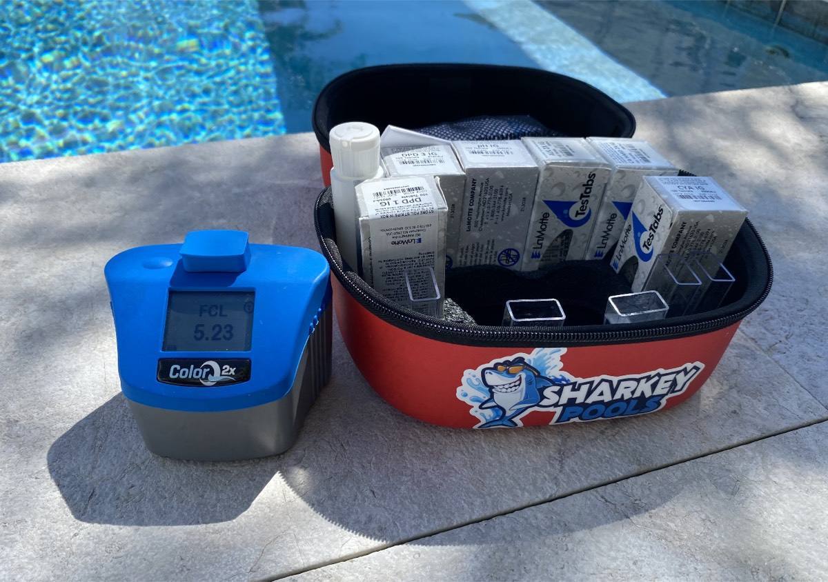 Digital pool water tester and Sharkey Pools chemical caddy on a pool deck
